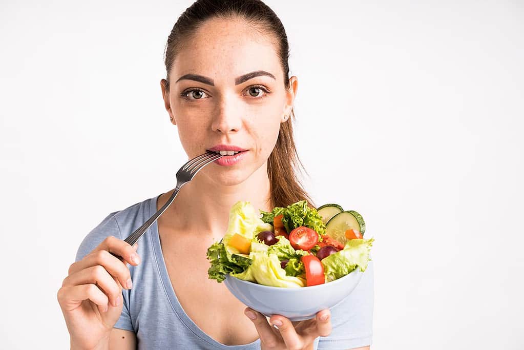 A close up of woman eating whole foods example salad