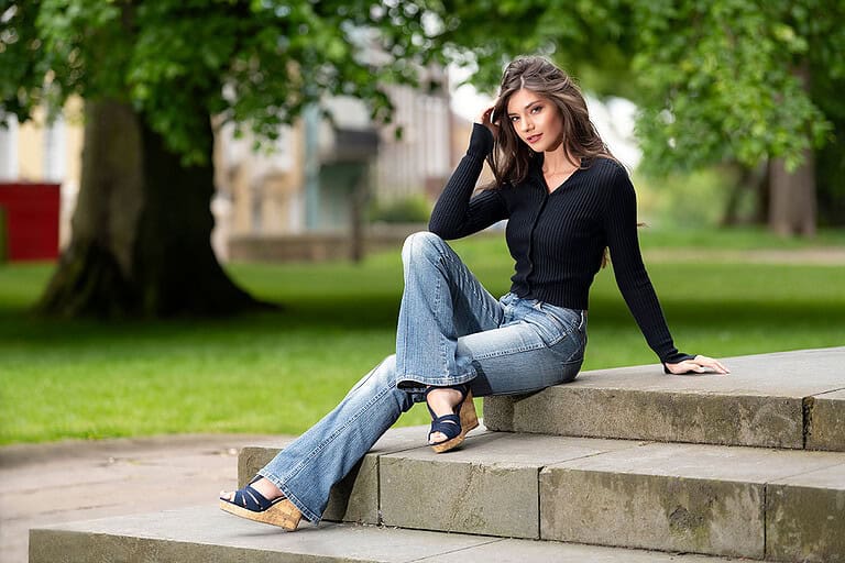 woman sitting on some steps in a park wearing Flared Denim jeans
