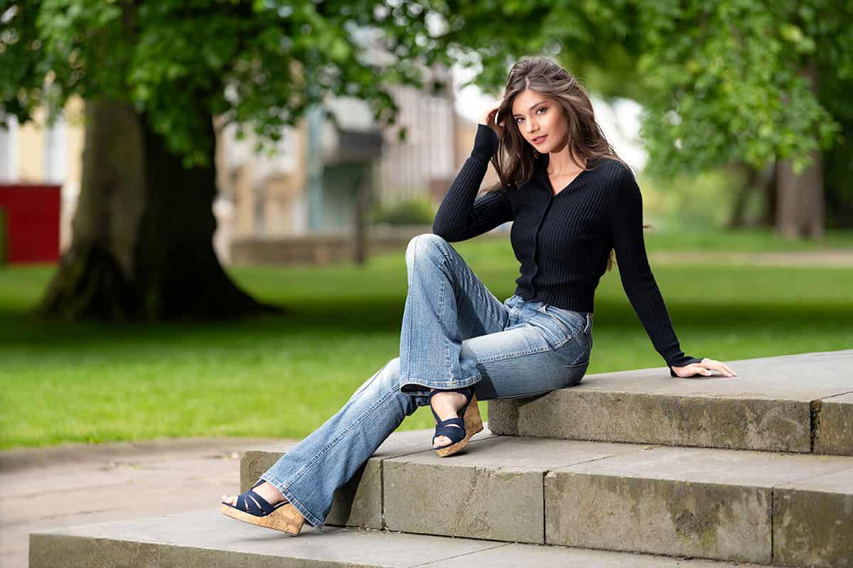 woman sitting on some steps in a park wearing Flared Denim jeans