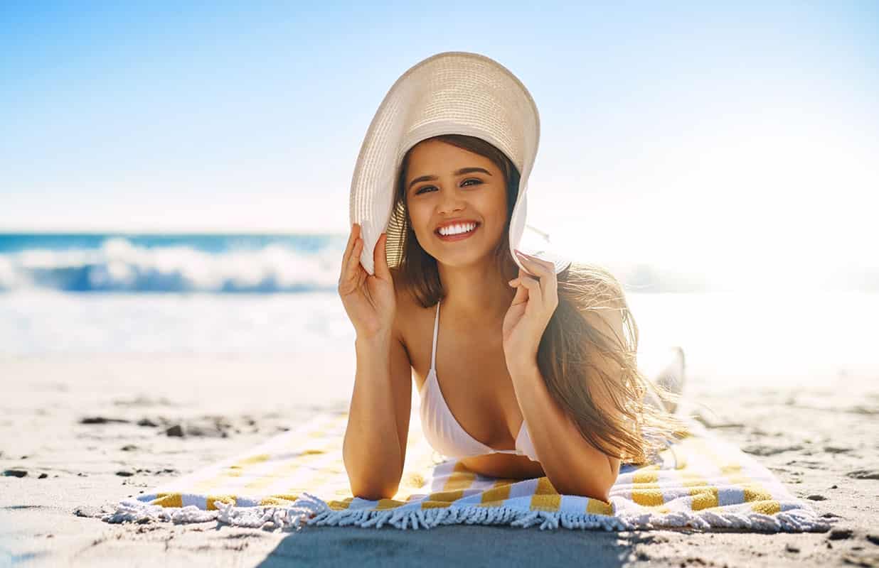 wpoman sun bathing on a beach on a warm sunney day. smiling